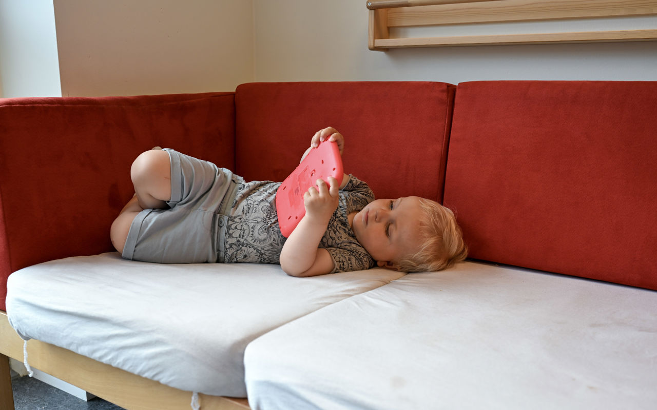 Barn ligger på sofa